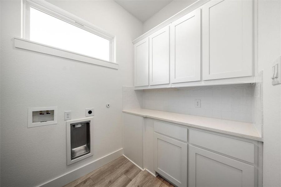 Laundry area with cabinet space, hookup for an electric dryer, light wood-type flooring, and hookup for a washing machine