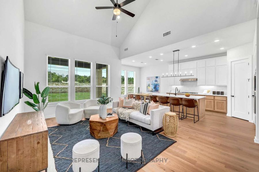 Living room with high vaulted ceiling, light wood-style flooring, a ceiling fan, and recessed lighting Living room with high vaulted ceiling, light wood-style flooring, a ceiling fan, and recessed lighting