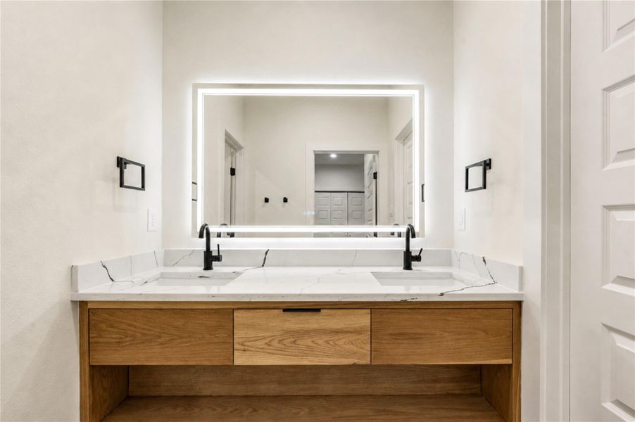 Elegant Jack and Jill bathroom for the 3rd and 4th bedrooms. Featuring a sleek, illuminated mirror above a modern vanity with a marble countertop and stylish black fixtures.