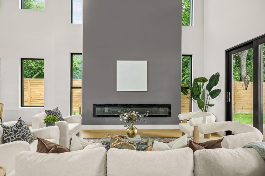 A spacious living room features soaring ceilings, a sleek modern fireplace, and expansive windows that invite the outdoors in. A spacious living room features soaring ceilings, a sleek modern fireplace, and expansive windows that invite the outdoors in.