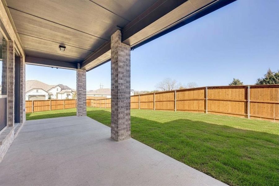 Covered patio with concrete flooring, brick columns, and a dark ceiling with an attached light fixture