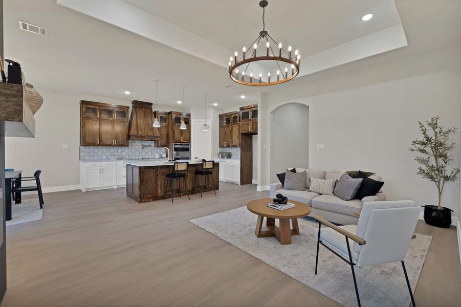 Living area with arched walkways, light wood-style floors, a chandelier, recessed lighting, and baseboards