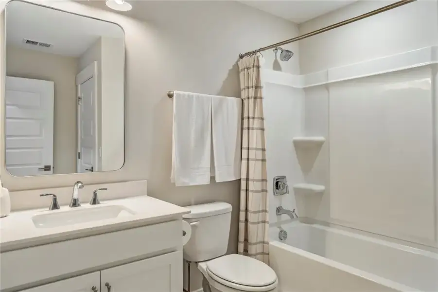 This bathroom features a sleek vanity, mirror, toi