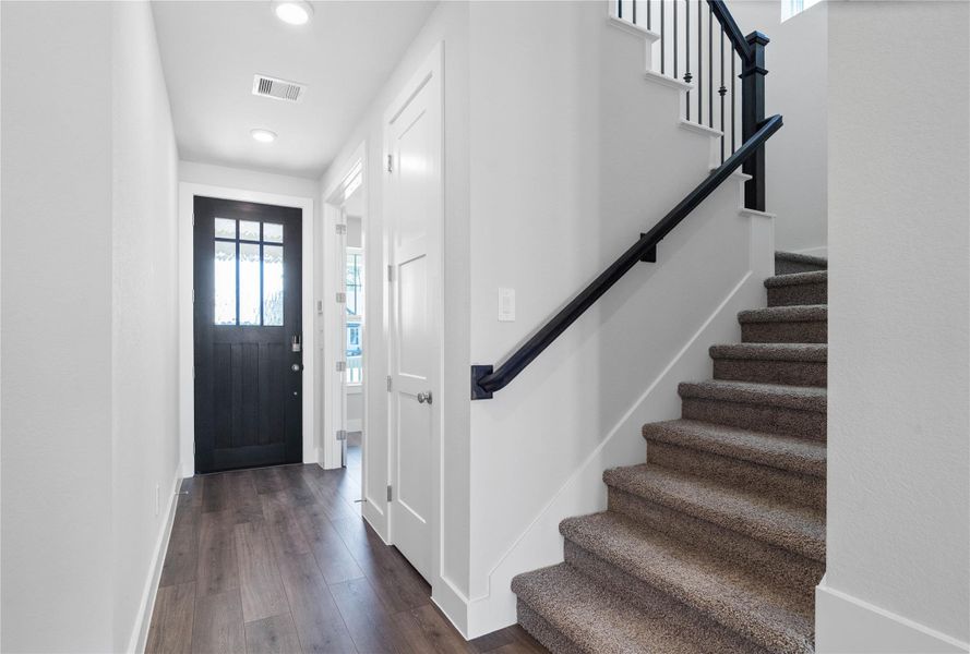 The staircase features a bold contrast of bright white risers and stringers against a striking matte black handrail, newel post, and iron balusters. The staircase features a bold contrast of bright white risers and stringers against a striking matte black handrail, newel post, and iron balusters.