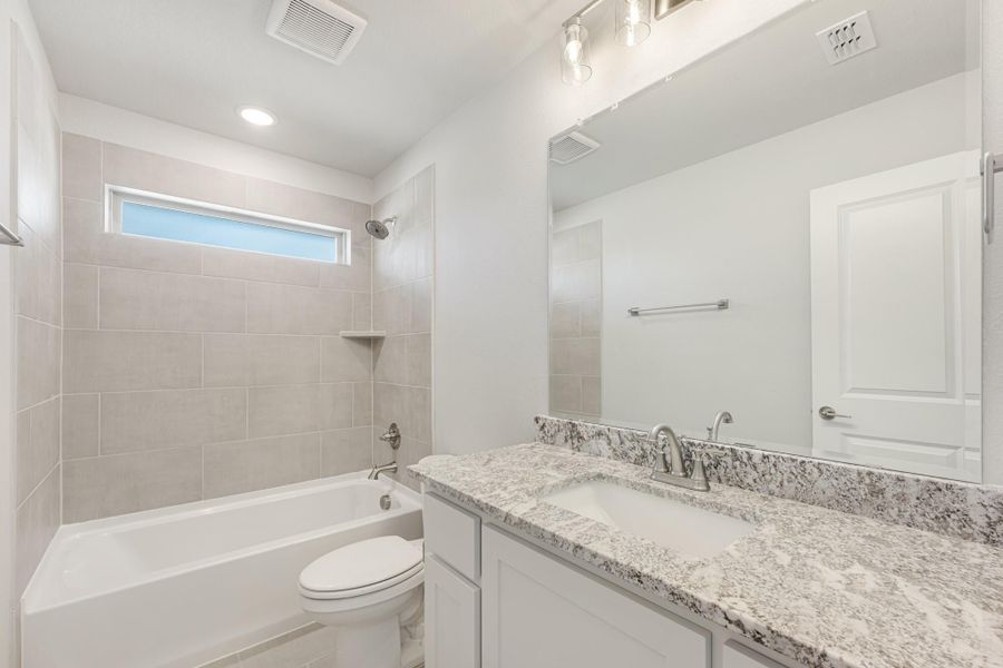 Bathroom with granite countertop vanity, white cabinets, tiled tub-shower combo, and large mirror Bathroom with granite countertop vanity, white cabinets, tiled tub-shower combo, and large mirror
