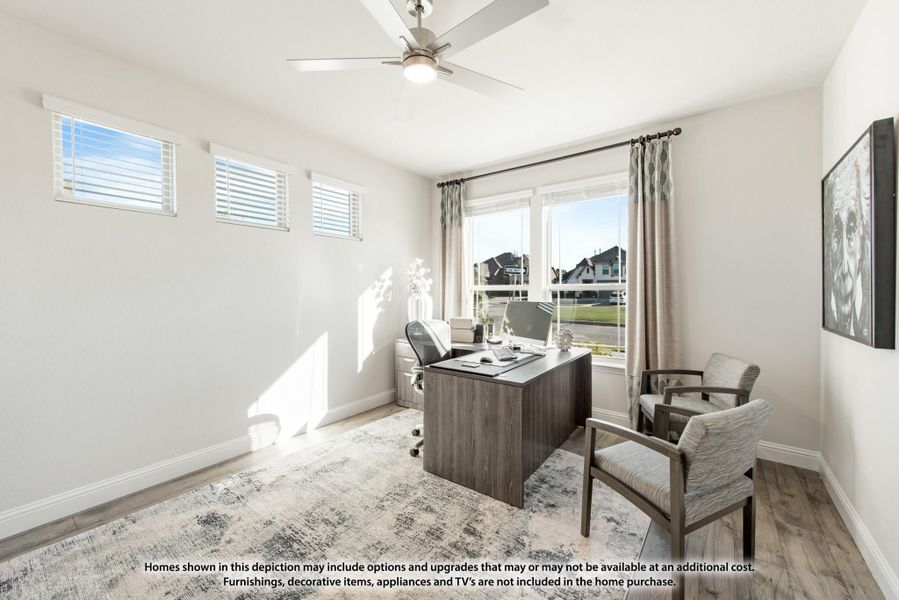 Home office with dark wood desk, ceiling fan, hardwood floors, and large window with neighborhood view