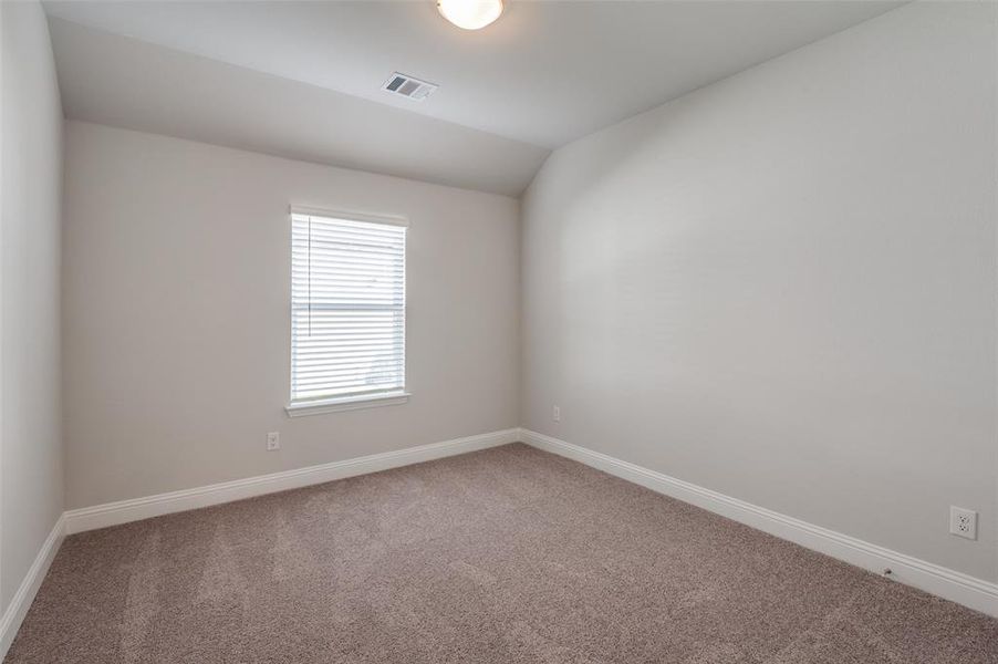 Carpeted spare room featuring vaulted ceiling