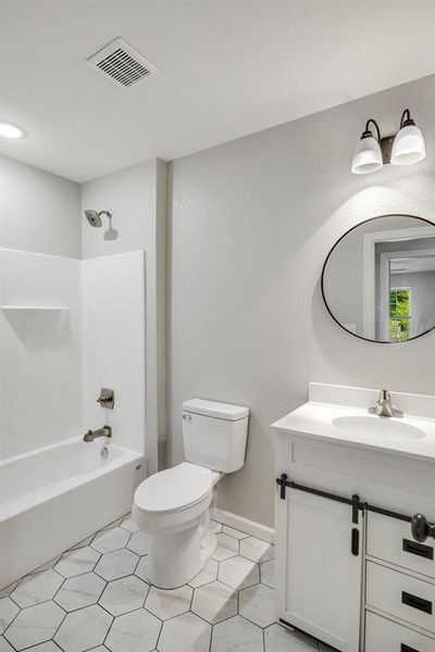 Bathroom with shower / tub combination, vanity, light tile patterned floors, and a textured wall Bathroom with shower / tub combination, vanity, light tile patterned floors, and a textured wall