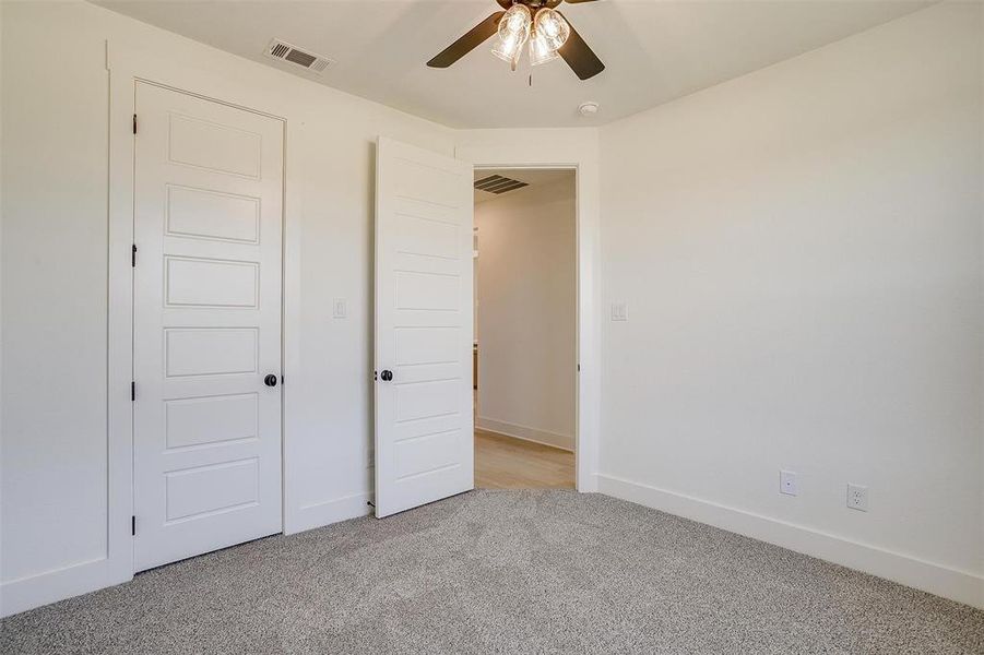 Unfurnished bedroom with light carpet and ceiling fan