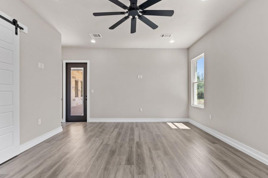 A versatile living space awaits, featuring wide plank flooring, a contemporary ceiling fan, and abundant natural light. A versatile living space awaits, featuring wide plank flooring, a contemporary ceiling fan, and abundant natural light.