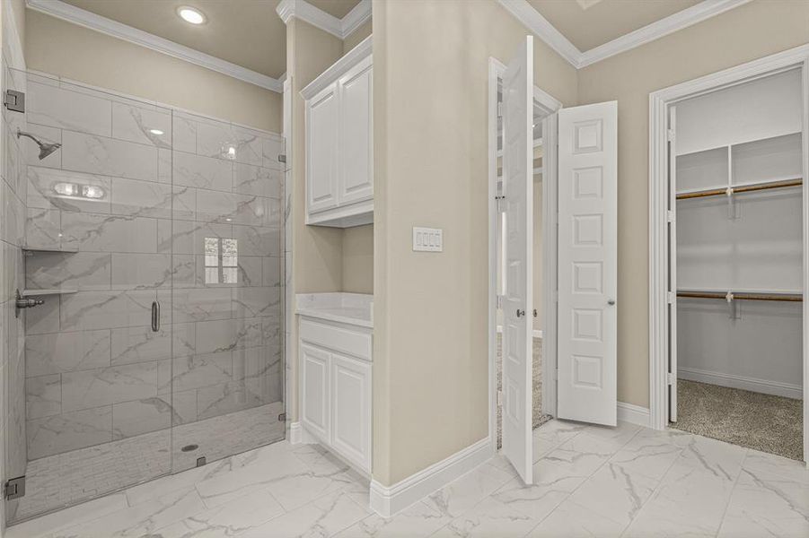 Bathroom featuring crown molding, a shower with door, and tile patterned floors