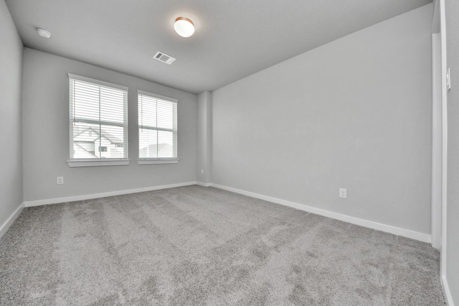 Secondary bedroom features plush carpeting, large windows that let in plenty of natural light, bright paint, and spacious closets. Sample photo of completed home with similar floor plan. Actual colors and selections may vary.