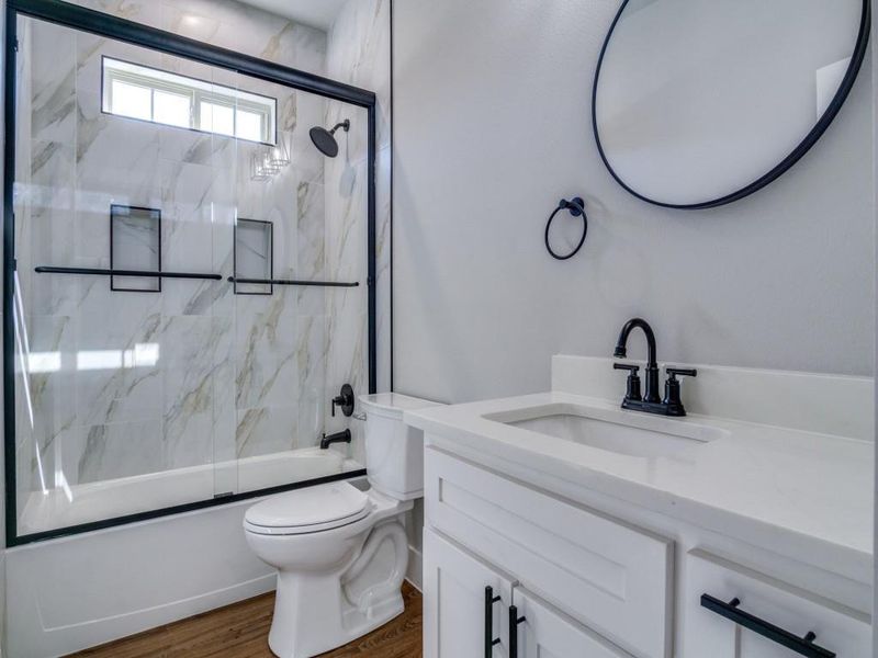 Full bathroom with combined bath / shower with glass door, vanity, hardwood / wood-style flooring, and toilet