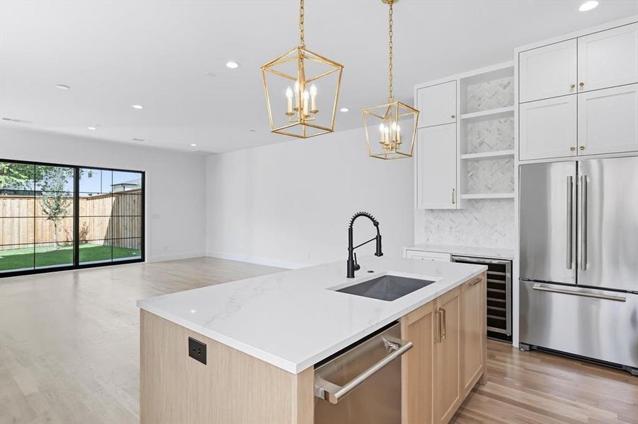Kitchen featuring stainless steel appliances, open floor plan, light wood finished floors, decorative light fixtures, and recessed lighting Kitchen featuring stainless steel appliances, open floor plan, light wood finished floors, decorative light fixtures, and recessed lighting