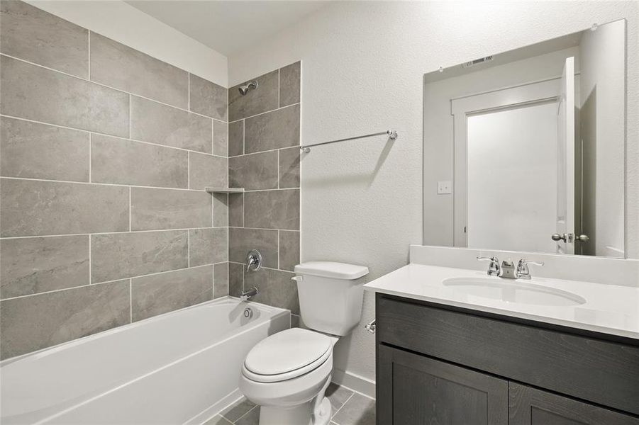 Full bath featuring a textured wall, vanity, tub / shower combination, and tile patterned flooring
