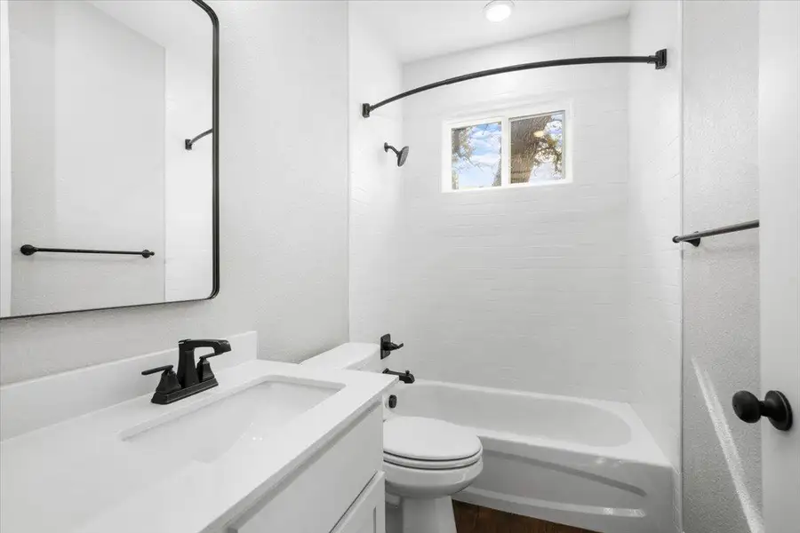 Bathroom featuring vanity, shower combination, toilet, and wood finished floors Bathroom featuring vanity, shower combination, toilet, and wood finished floors