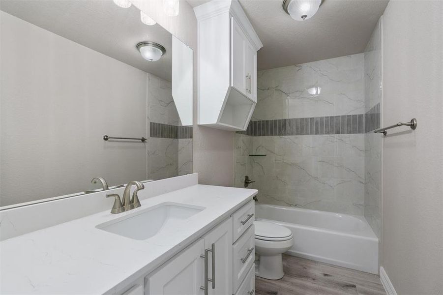 Bathroom featuring a white vanity with an integrated sink, brushed nickel faucet, large wall mirror, and a built-in medicine cabinet Bathroom featuring a white vanity with an integrated sink, brushed nickel faucet, large wall mirror, and a built-in medicine cabinet