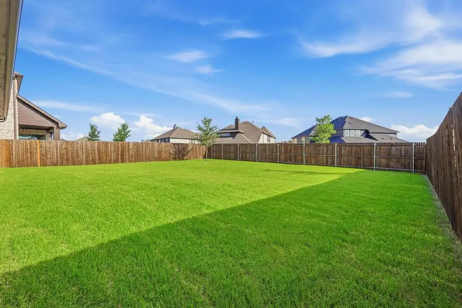 Expansive backyard featuring a lush, green lawn and a full privacy fence