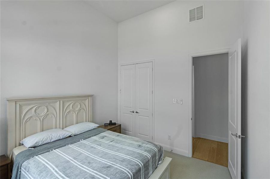 Vaulted ceiling room featuring light-colored carpet, white walls, double-panel closet doors, and an additional doorway leading to a hardwood-finish hallway