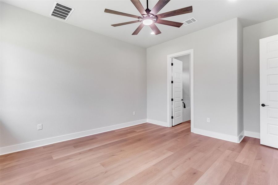 Empty room with a ceiling fan and light wood finished floors
