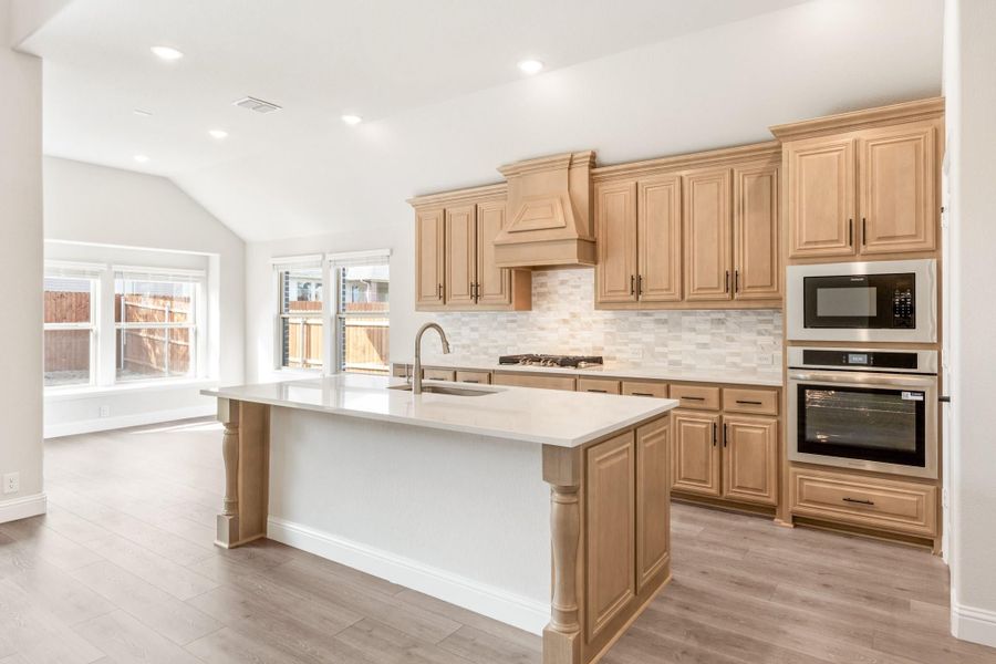 Kitchen with light wood cabinets, center island, stainless steel appliances, and tile backsplash Kitchen with light wood cabinets, center island, stainless steel appliances, and tile backsplash