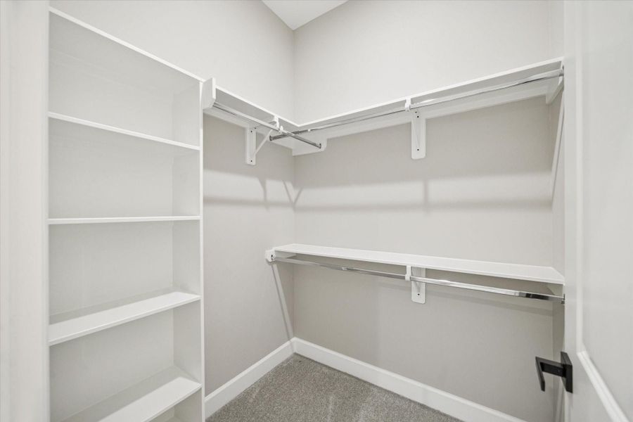 Secondary bedroom closet with built-in shelving and upper and lower hanging bars.