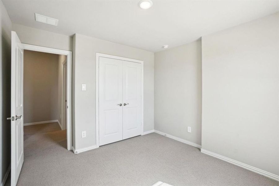 Unfurnished bedroom featuring light carpet and a closet Unfurnished bedroom featuring light carpet and a closet