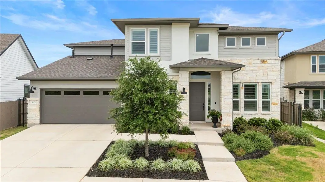 Prairie-style home with stone siding, roof with shingles, driveway, and an attached garage