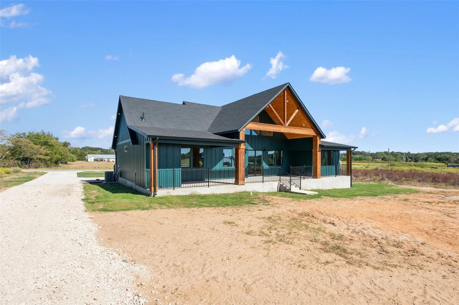 View of front facade featuring board and batten siding, a shingled roof, and driveway