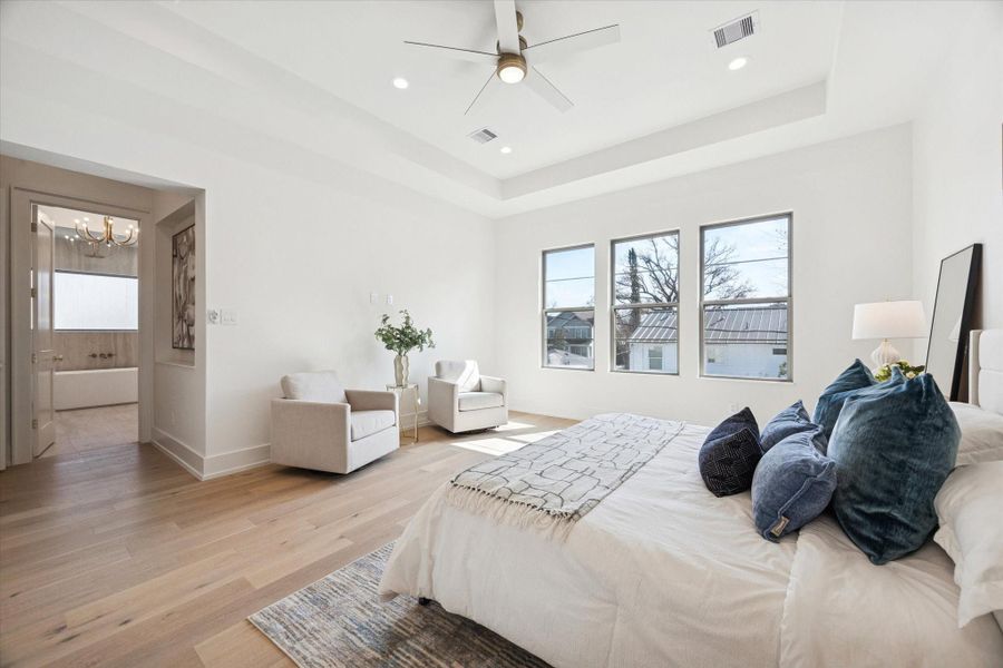 Another view of the primary suite offering a glimpse into the spa-like primary bathroom.