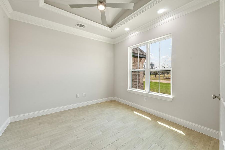 Unfurnished room featuring light wood finished floors, ornamental molding, a tray ceiling, recessed lighting, and a ceiling fan