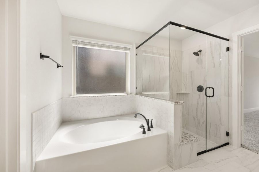 Master bathroom with soaking tub, glass-enclosed shower, marble tile walls, and black fixtures