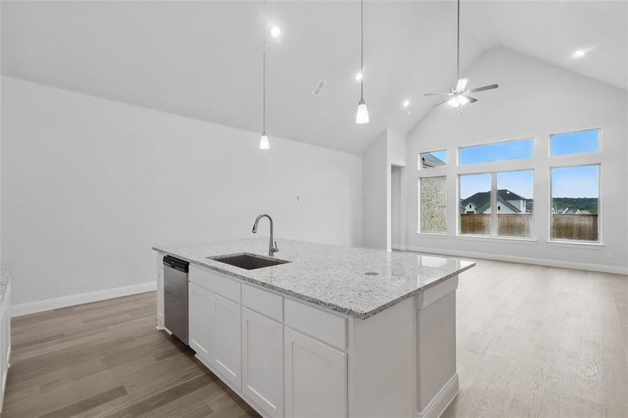 Kitchen featuring a sink, stainless steel dishwasher, open floor plan, white cabinetry, and high vaulted ceiling Kitchen featuring a sink, stainless steel dishwasher, open floor plan, white cabinetry, and high vaulted ceiling