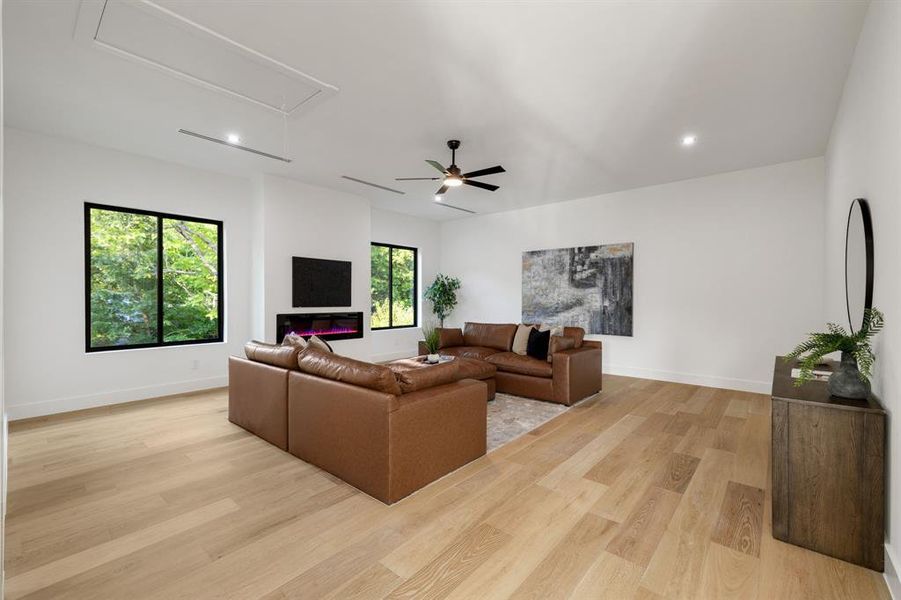 Spacious room featuring wood-finish flooring, a contemporary linear fireplace, and recessed ceiling lighting