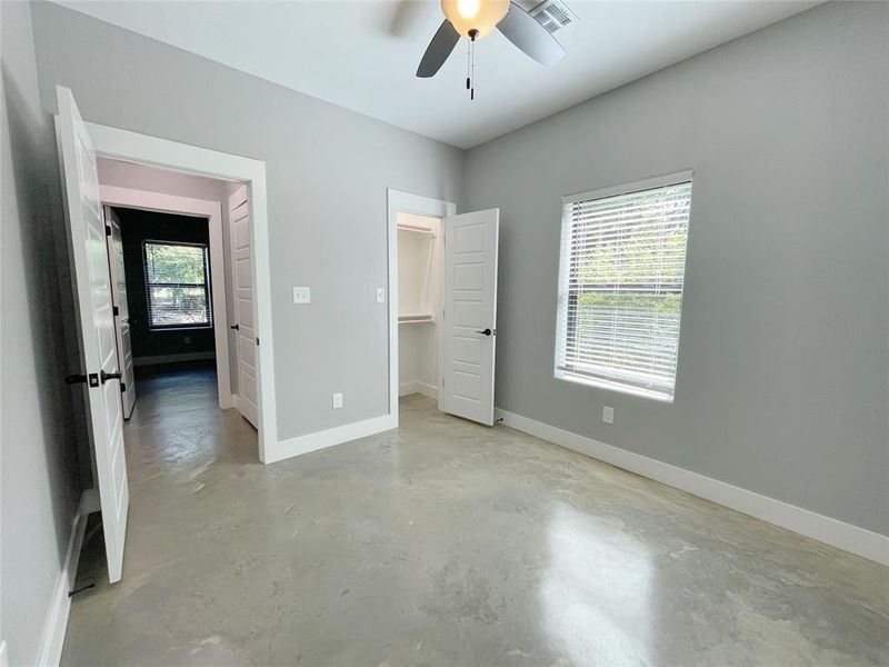 Unfurnished bedroom featuring a walk in closet, ceiling fan, and a closet