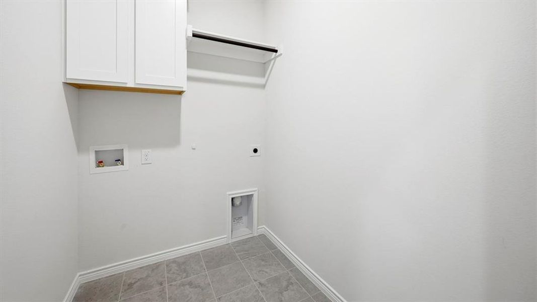 Laundry area featuring cabinet space, electric dryer hookup, washer hookup, and light tile patterned floors