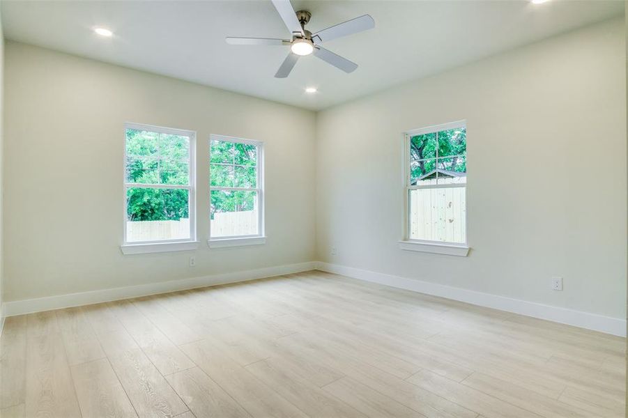 Empty room featuring baseboards, a wealth of natural light, and light wood finished floors