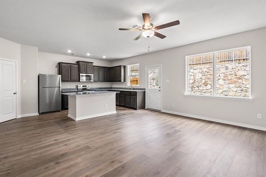 Kitchen with stainless steel appliances, a center island, dark brown cabinets, light wood finished floors, and a ceiling fan Kitchen with stainless steel appliances, a center island, dark brown cabinets, light wood finished floors, and a ceiling fan