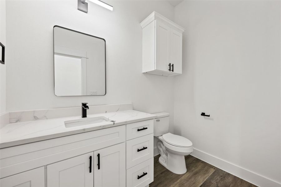 Contemporary bathroom featuring a white vanity with black hardware, an integrated sink, and a white countertop with subtle veining