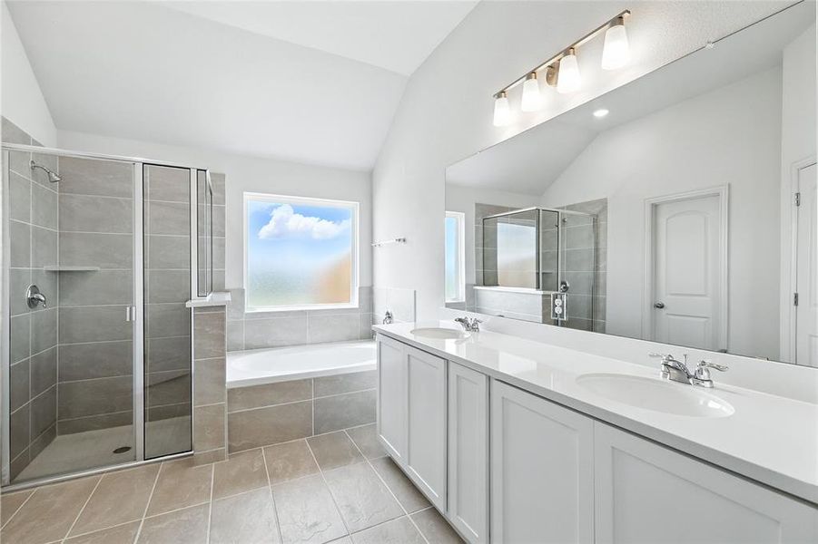 Full bathroom featuring a garden tub, double vanity, a stall shower, lofted ceiling, and light tile patterned flooring Full bathroom featuring a garden tub, double vanity, a stall shower, lofted ceiling, and light tile patterned flooring