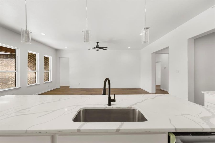 Kitchen featuring decorative light fixtures, light stone countertops, and sink