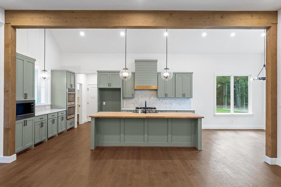 Kitchen featuring green cabinetry, hanging light fixtures, backsplash, an island with sink, and recessed lighting Kitchen featuring green cabinetry, hanging light fixtures, backsplash, an island with sink, and recessed lighting