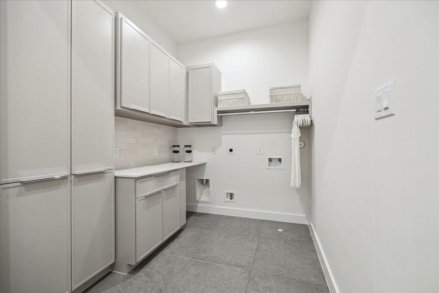 Spacious utility room with extensive cabinetry, ample counter space, and built-in storage solutions. Clean tile flooring and bright finishes create a practical yet polished environment. The thoughtfully planned layout provides convenience and efficiency while maintaining the home’s cohesive modern aesthetic.