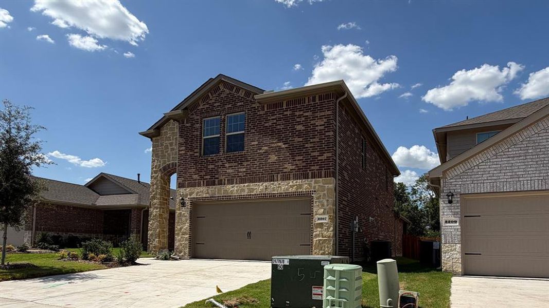 Two-story residence featuring a brick and stone facade, arched entryway, and an attached two-car garage Two-story residence featuring a brick and stone facade, arched entryway, and an attached two-car garage