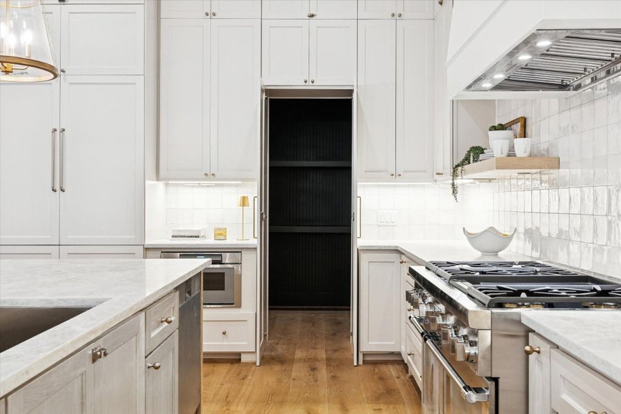 Stylish kitchen featuring premium appliances, ample cabinetry, Taj Mahal quartzite counters, and a generous walk-in pantry.