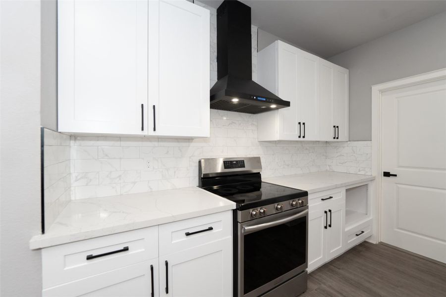 This modern kitchen features a stylish range hood that complements its sleek design. With high-end finishes, ample storage, and a spacious layout, it’s the perfect space for cooking and entertaining in comfort.