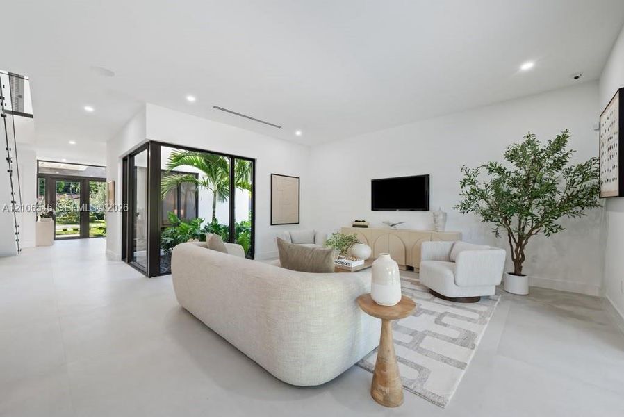 Living space featuring smooth surface flooring, recessed lighting, and floor-to-ceiling black-framed glass wall panels