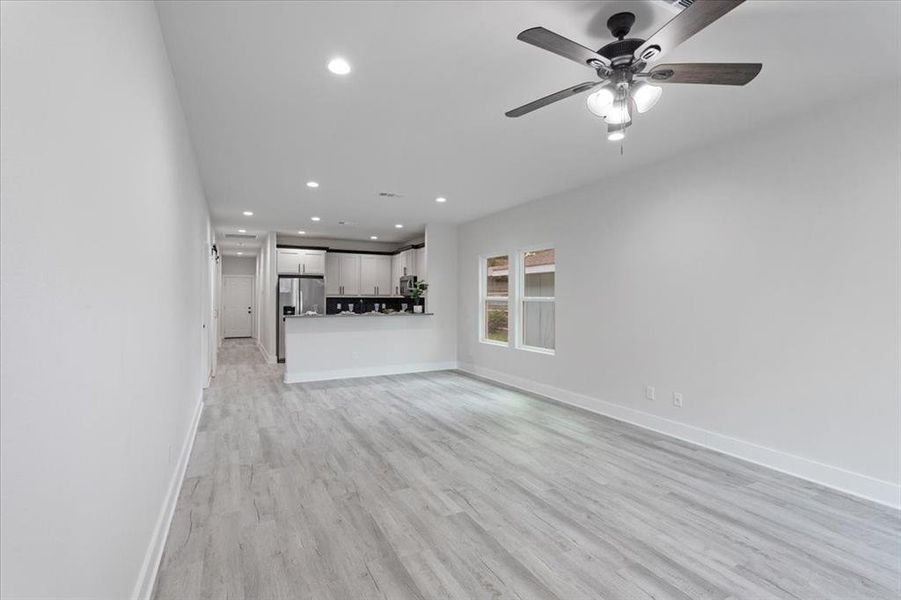 Unfurnished living room featuring ceiling fan and light hardwood / wood-style floors