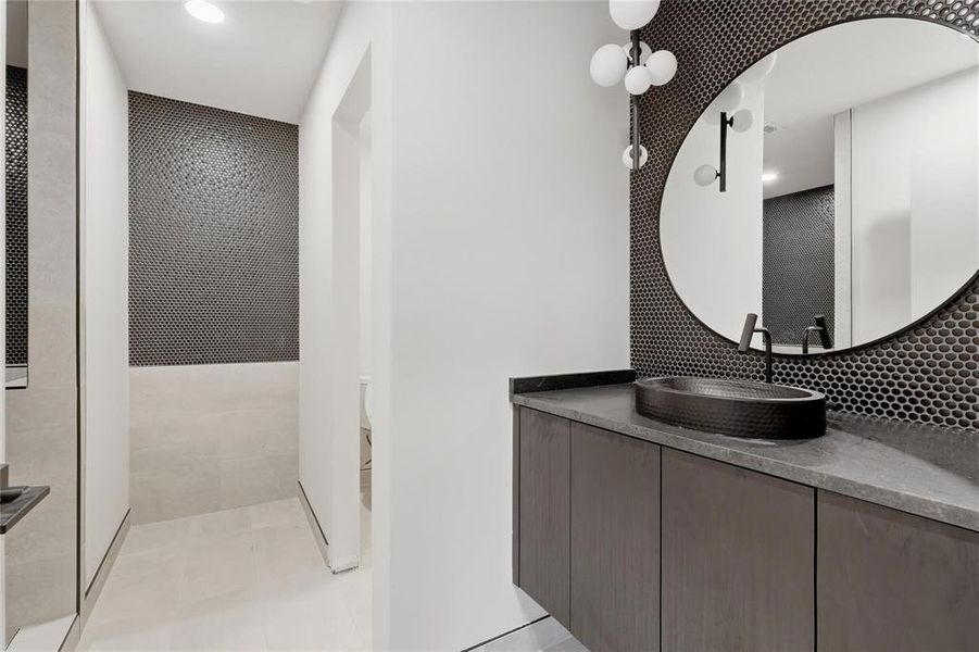 Modern bathroom vanity featuring a dark countertop, an oval vessel sink, and a black wall-mounted faucet