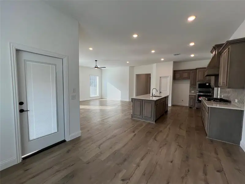 Kitchen featuring open floor plan, a ceiling fan, recessed lighting, quartz countertops, an island with dual sink, and built-in microwave/oven combination Kitchen featuring open floor plan, a ceiling fan, recessed lighting, quartz countertops, an island with dual sink, and built-in microwave/oven combination